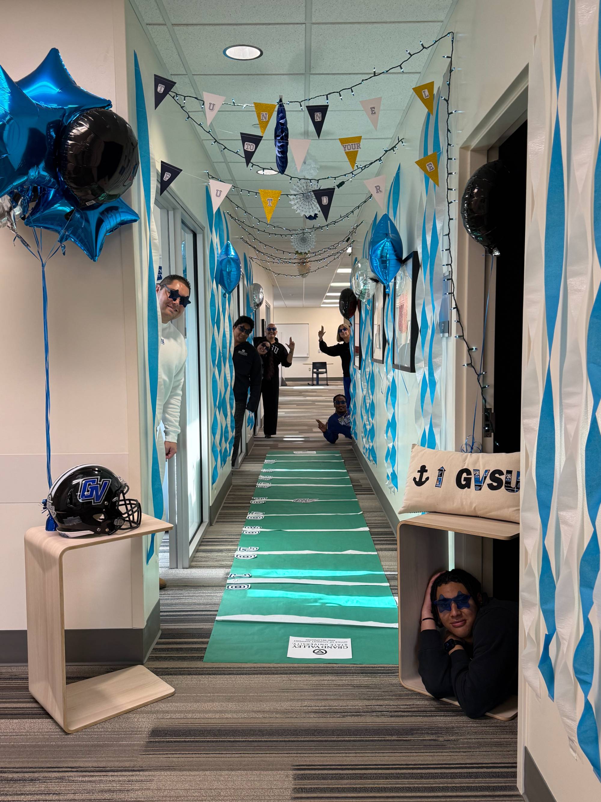 OSSB Homecoming decorations, office hallway turned into a football field, with team members smiling from their doorways